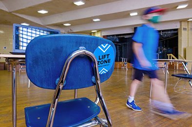 chair with Lift sticker, desk, and student walking in community center