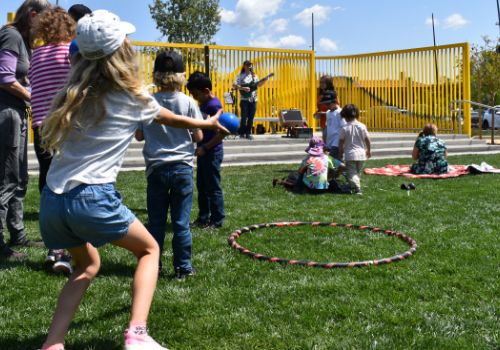 A child plays a game with a ball and hula hoop