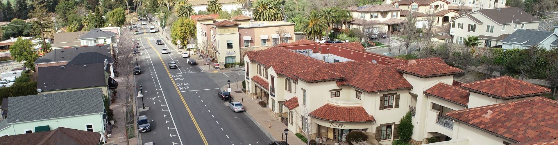 commercial corridor with street, buildings, and hills