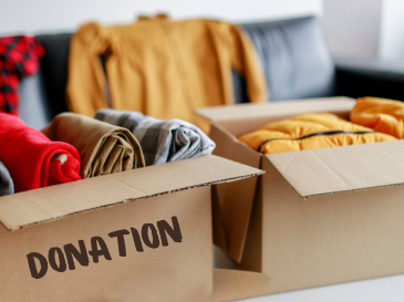 Photo of a donation box with clothes and a hat on top of it