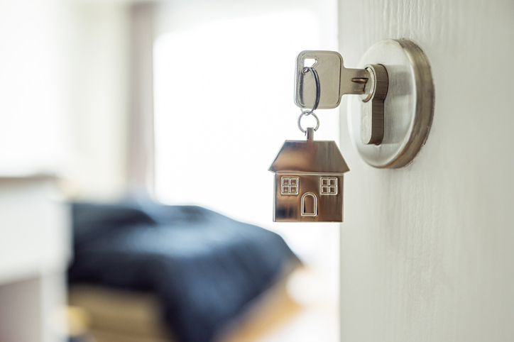 An entrance to an apartment with a bed and a key in the door